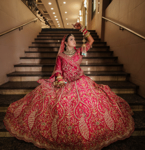 Bride sitting gracefully on staircase wearing bridal lehenga