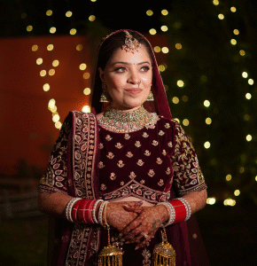 Bride posing in detailed red lehenga with festive lighting
