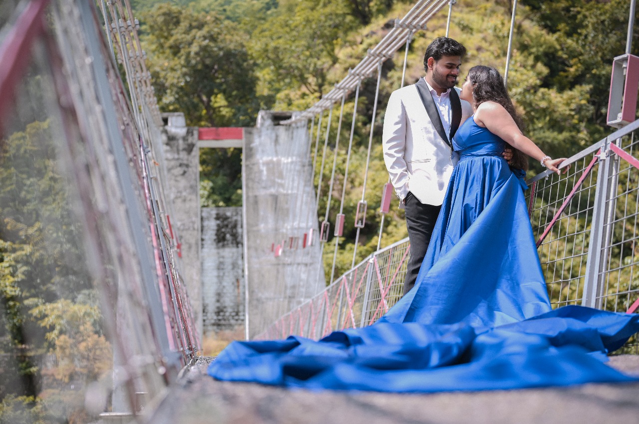 Bride posing near waterfall in long blue gown during pre wedding shoot